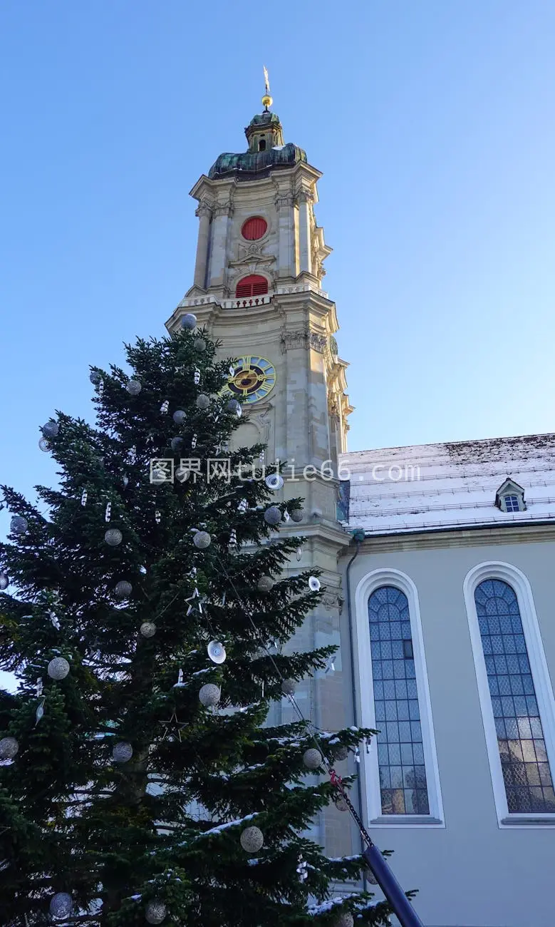 瑞士小镇雪景中圣尼古拉斯教堂与节日树辉映图片