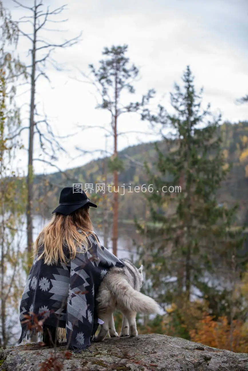 帽毯妇女雪犬望湖景图片