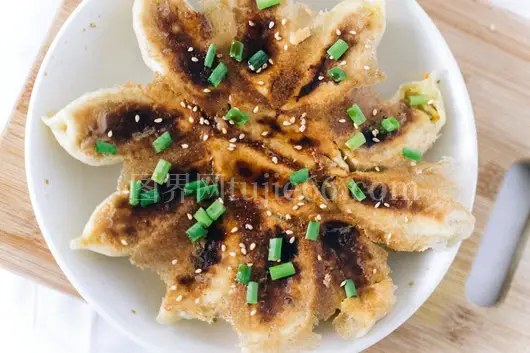 金黄煎饺撒葱花芝麻盘上