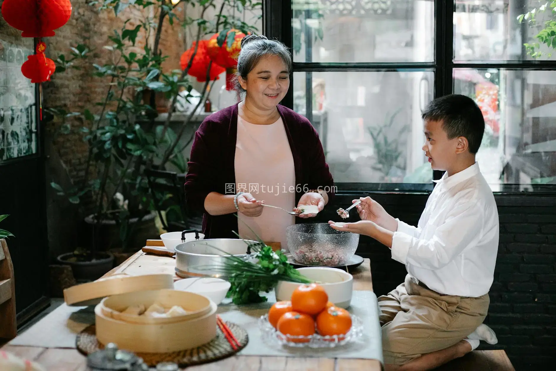 亚裔少年厨房助祖母包饺子图片