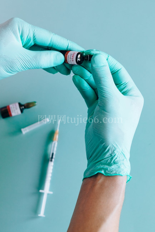 手套手操作疫苗瓶注射器青绿背景特写