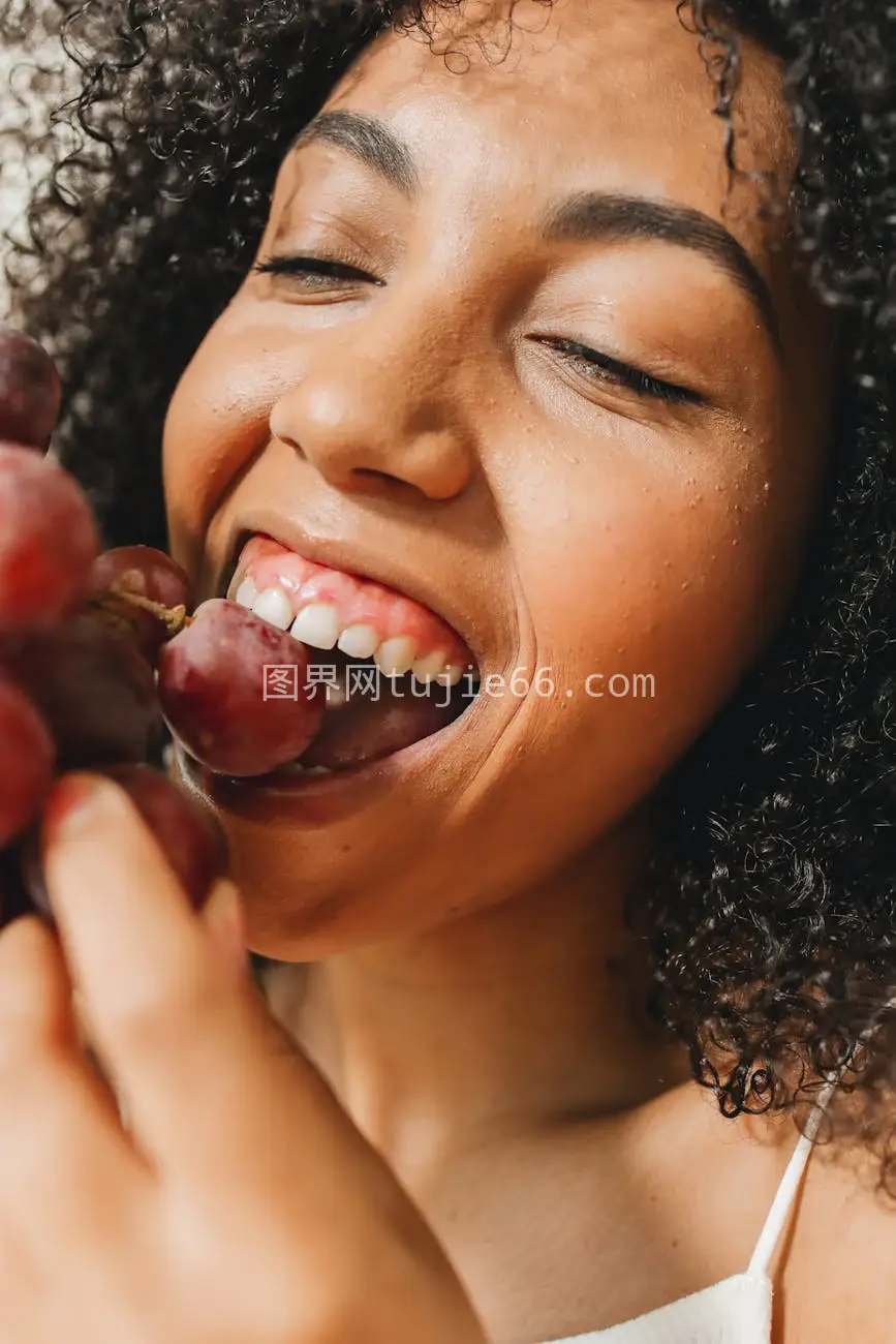 快乐卷发女士享新鲜葡萄健康饮食图片