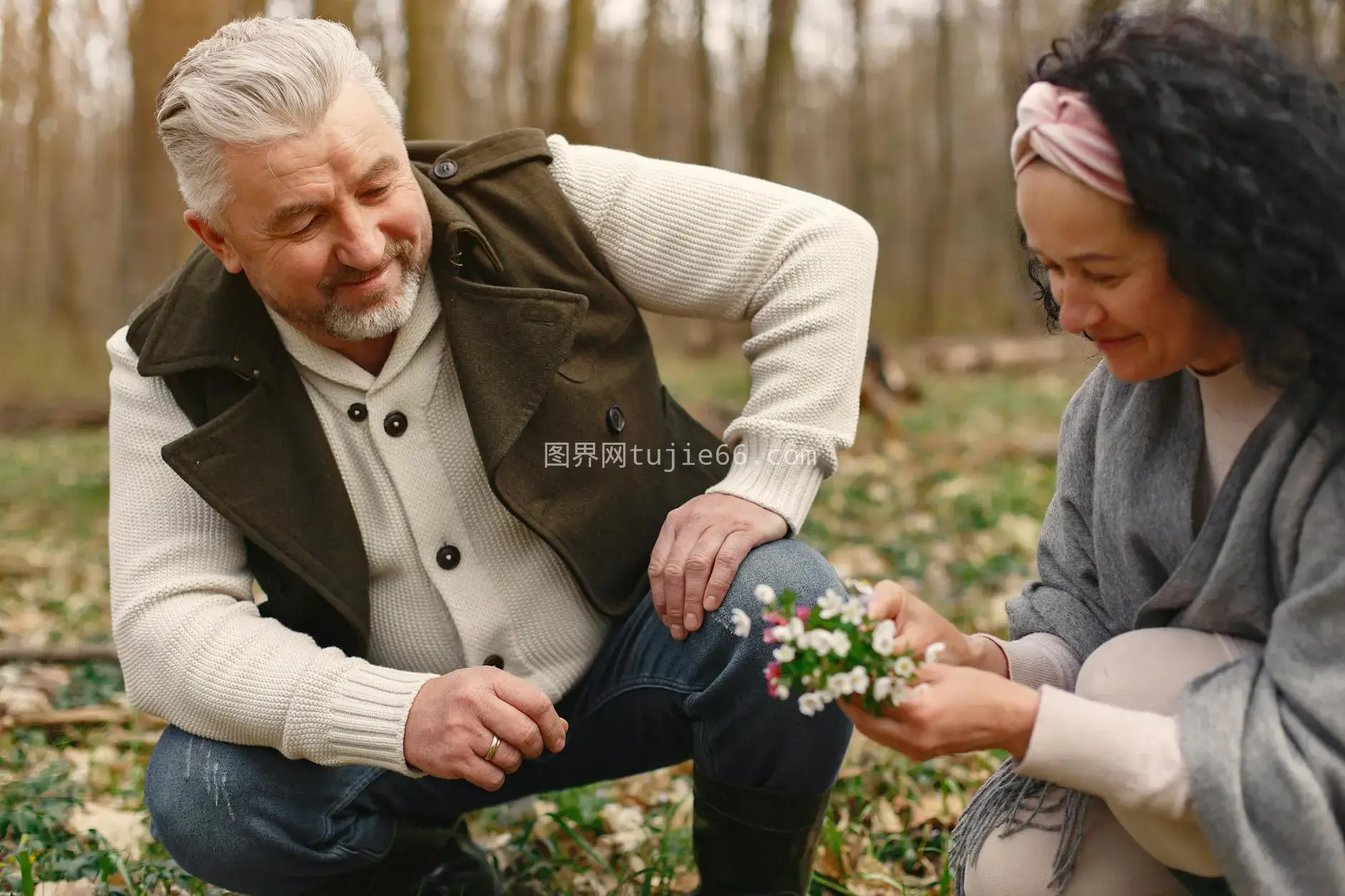 秋日森林老夫妇携手漫步，妻子微笑捧花图片