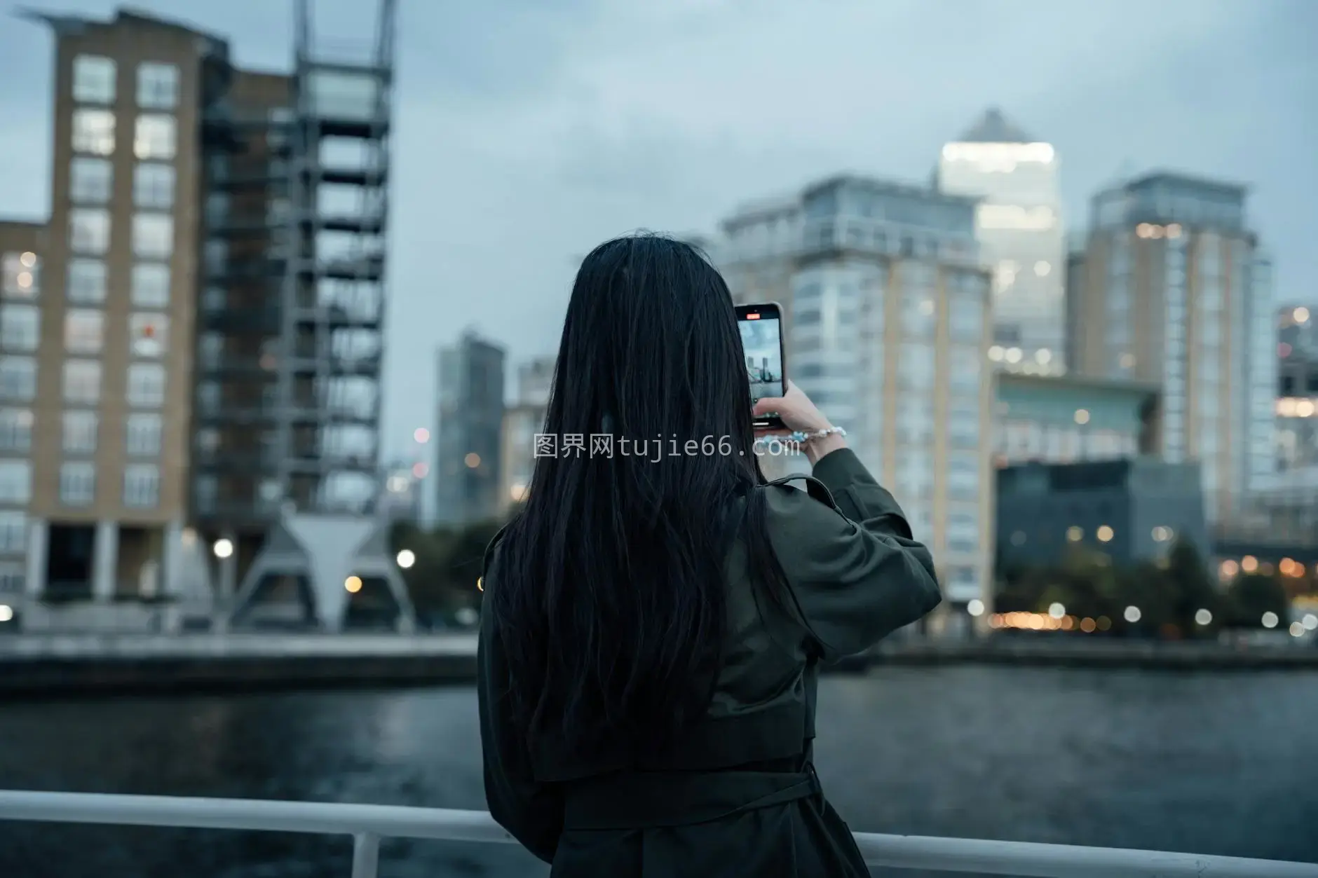 黄昏女性拍城市天际线映河对岸建筑图片