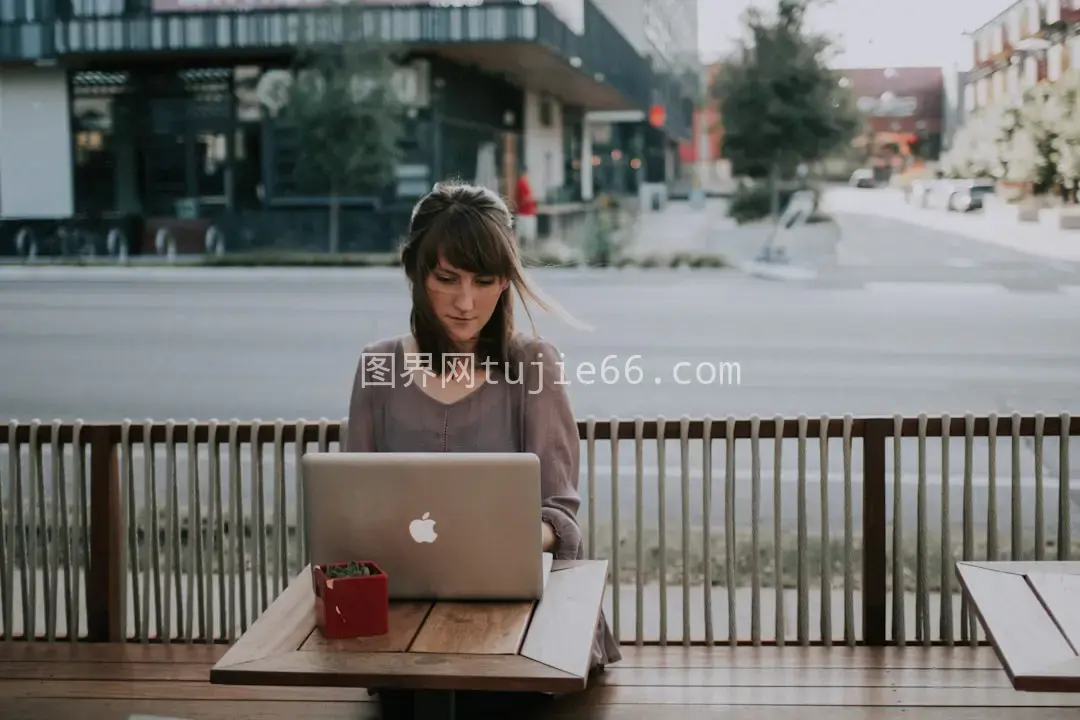 女性灰衫长椅前用MacBook图片