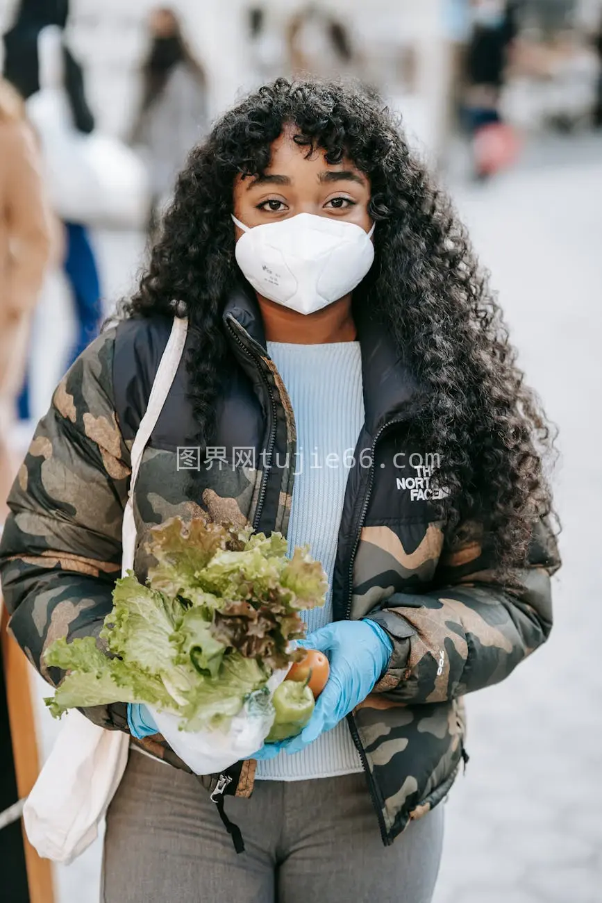 非裔女性街头戴口罩持菜图片