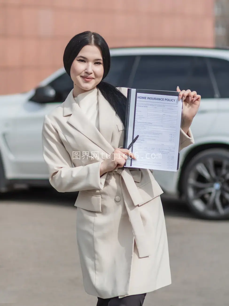 微笑女性手持家庭保险单户外场景图片