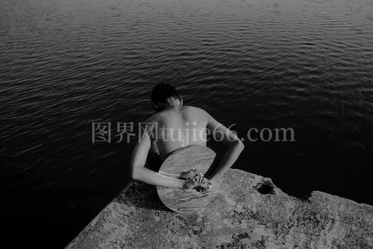 男子背镜岩石岛望水景