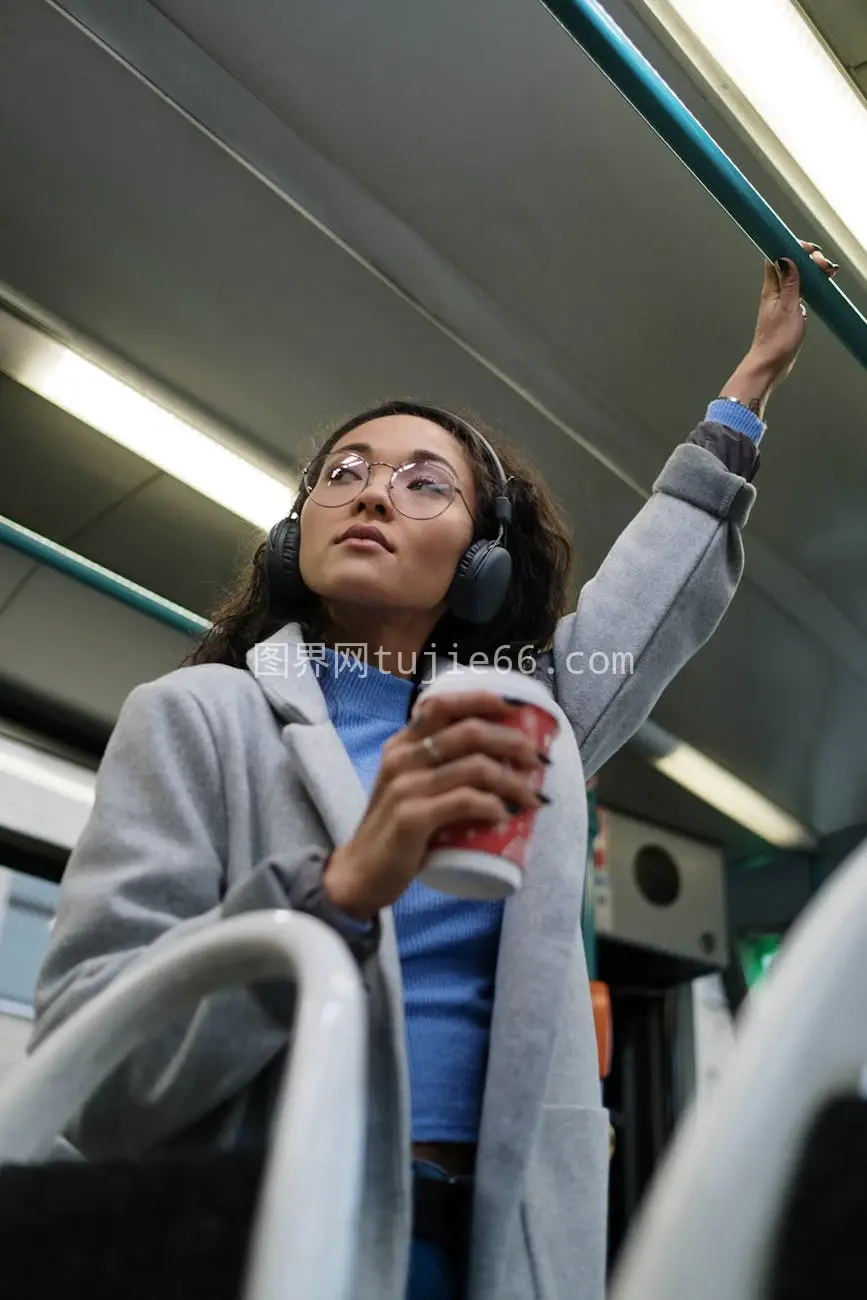 耳机伴音乐，年轻女性火车上享受通勤时光图片