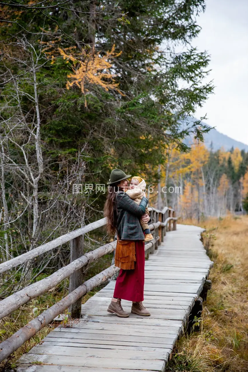 妇女抱子秋日漫步风景道图片