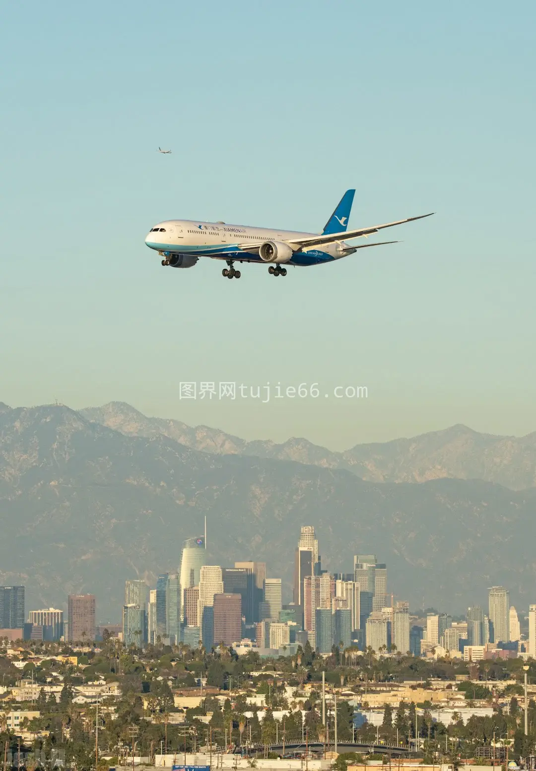 白色蓝客机飞越建筑上空图片