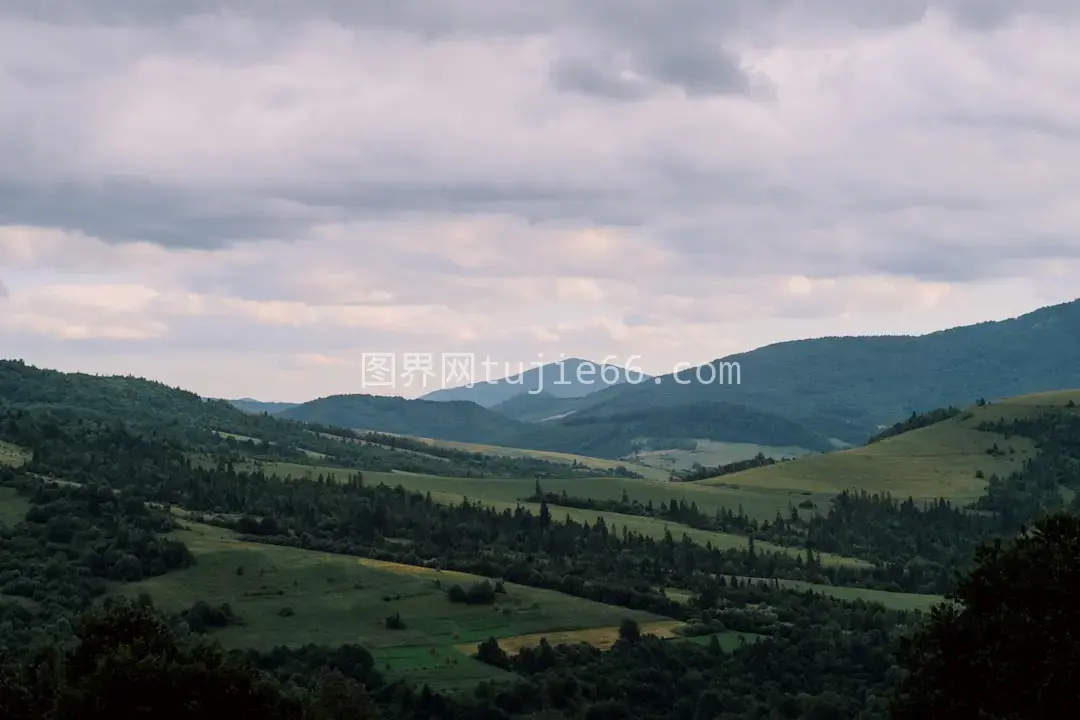 绿色平原树木环绕山脉白天景致图片