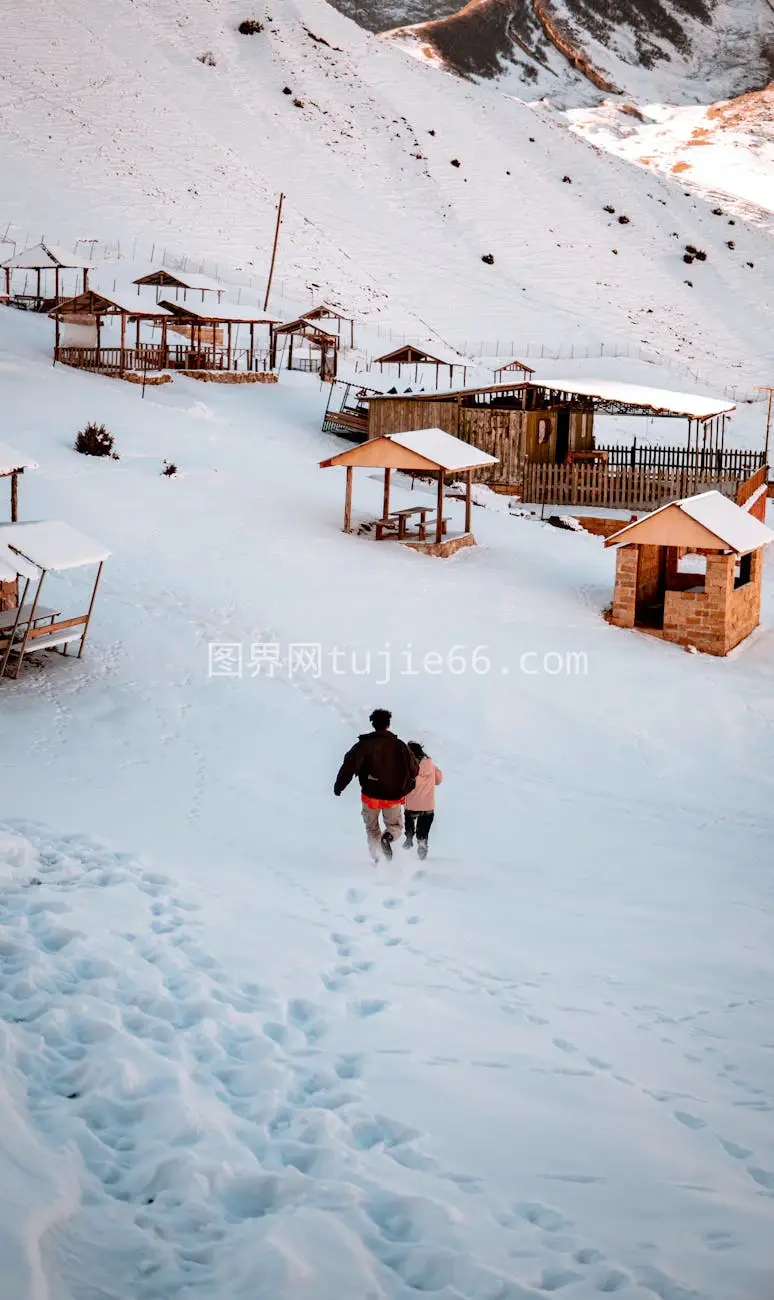 雪地山腰木屋映衬群山冬景图片