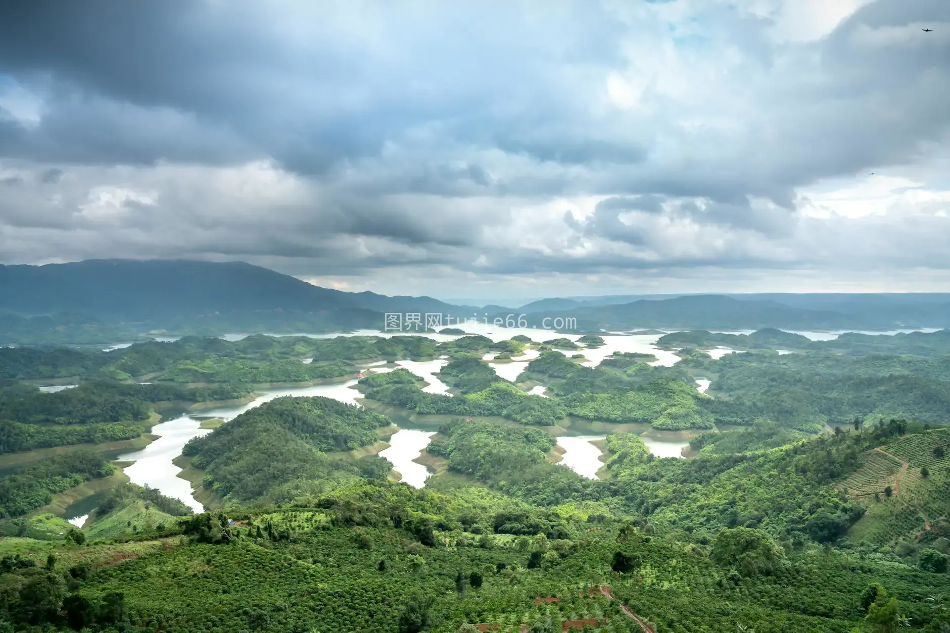 空中视角映照绿色湖泊山丘多云天空图片