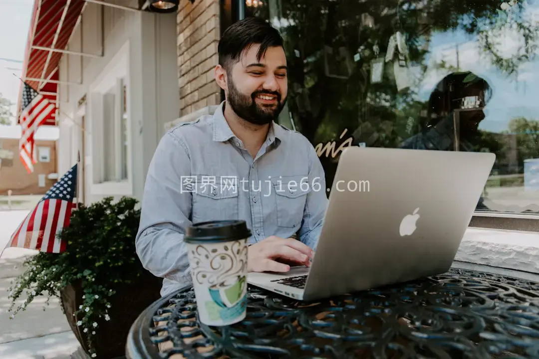 男士穿灰衬衫微笑用MacBook图片