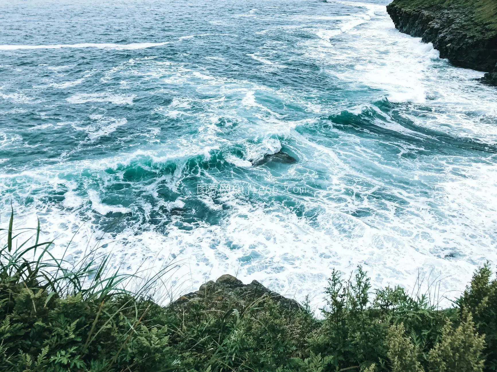 上方视角碧海拍打绿岩图片