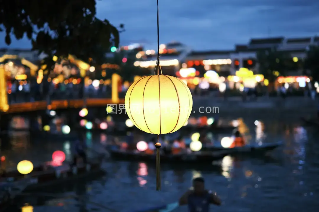 树木上挂灯笼水面映照夜色美图片