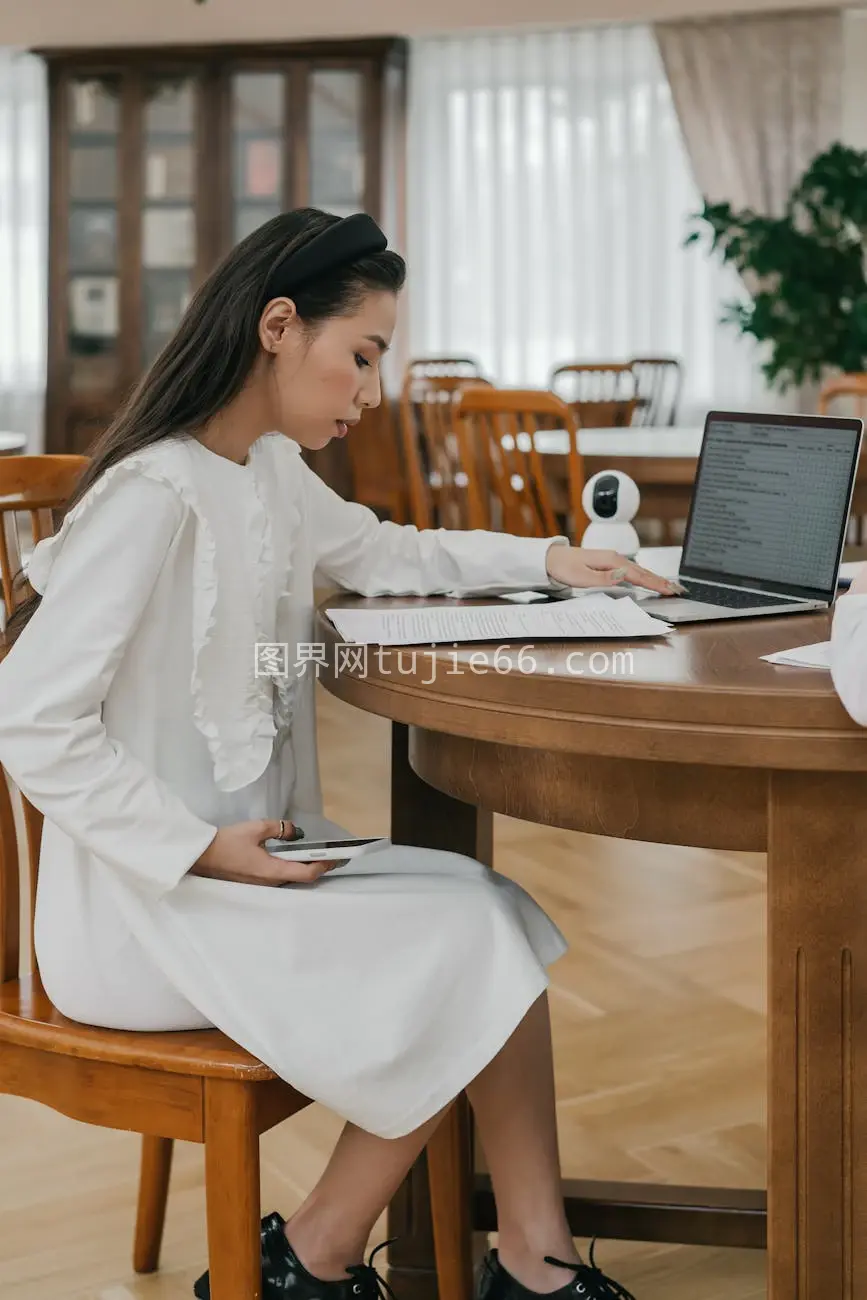 成年女性白色连衣裙木质桌旁在线学习图片