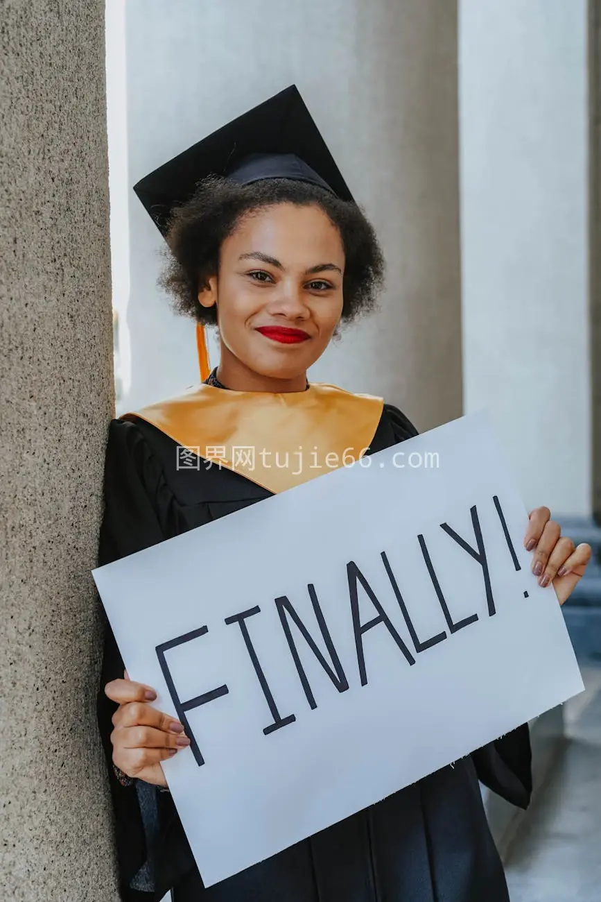 女大学生毕业礼服手持Finally!标志庆祝成就图片