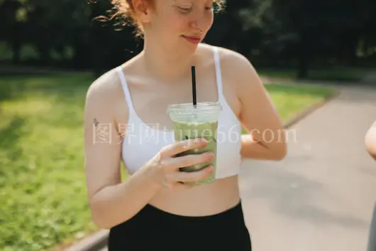 白女手持绿冰饮公园景