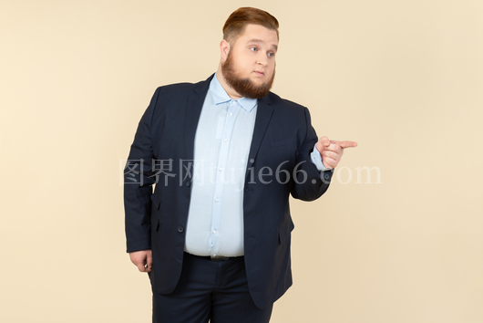 严肃年轻肥胖男子西装指向上图
