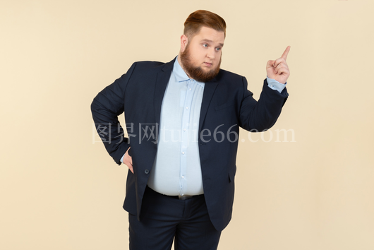 严肃年轻肥胖西装男向上指