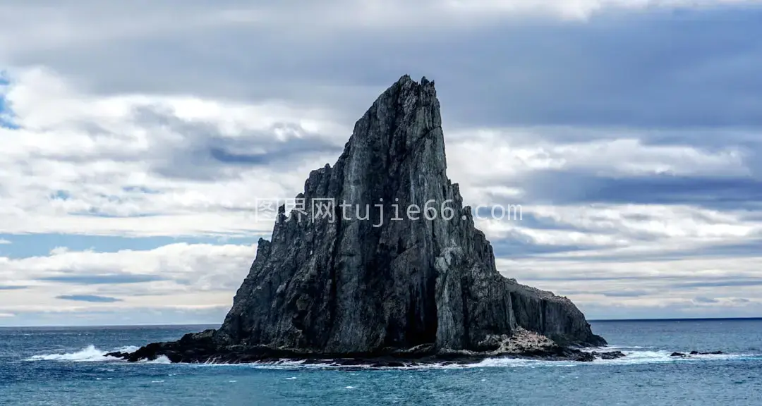 白日蓝天白云下灰色岩石映衬大海图片