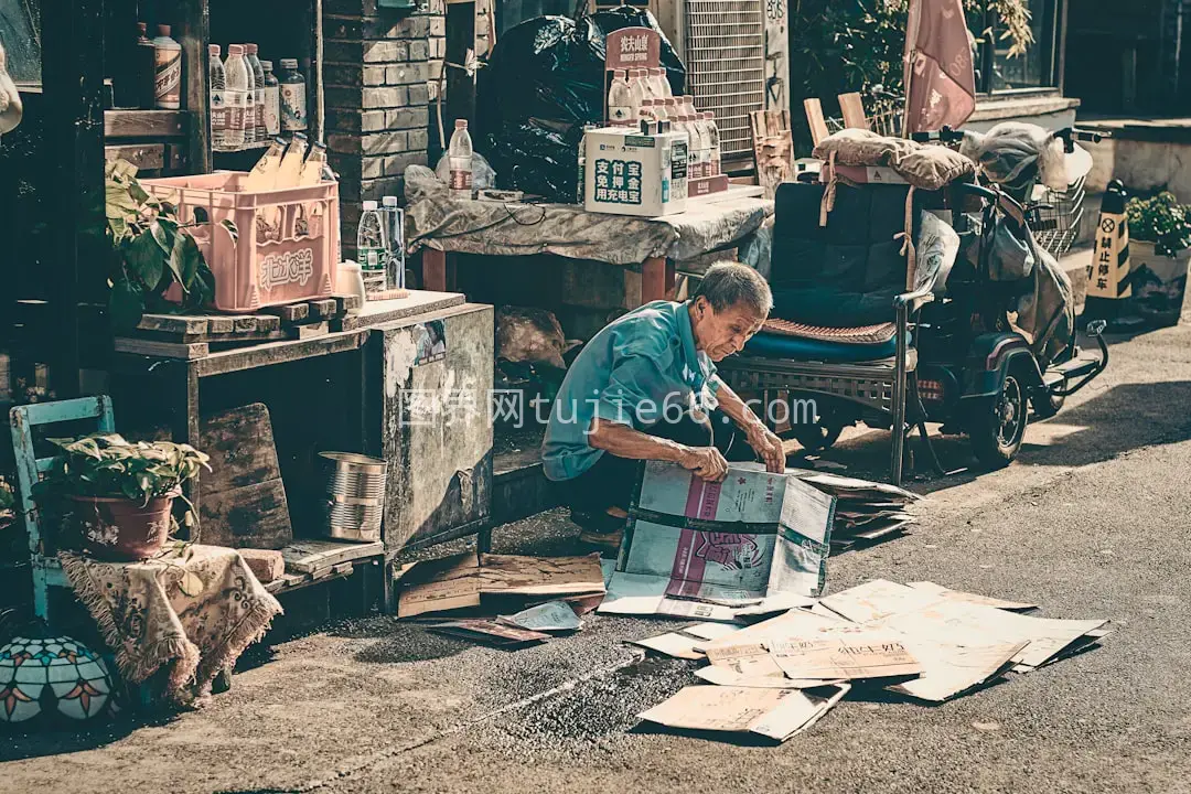 蓝色T恤男子椅上读报图片