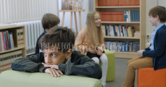 男孩独坐众孩嬉戏间