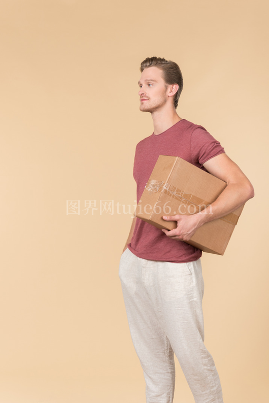 快递员手插口袋手持包裹站立