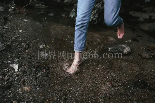 赤脚跳跃岩石溪流中蓝牛仔裤人