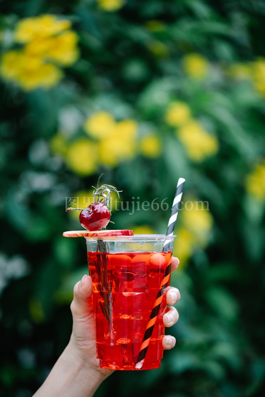 户外红樱桃饮品特写模糊绿背景