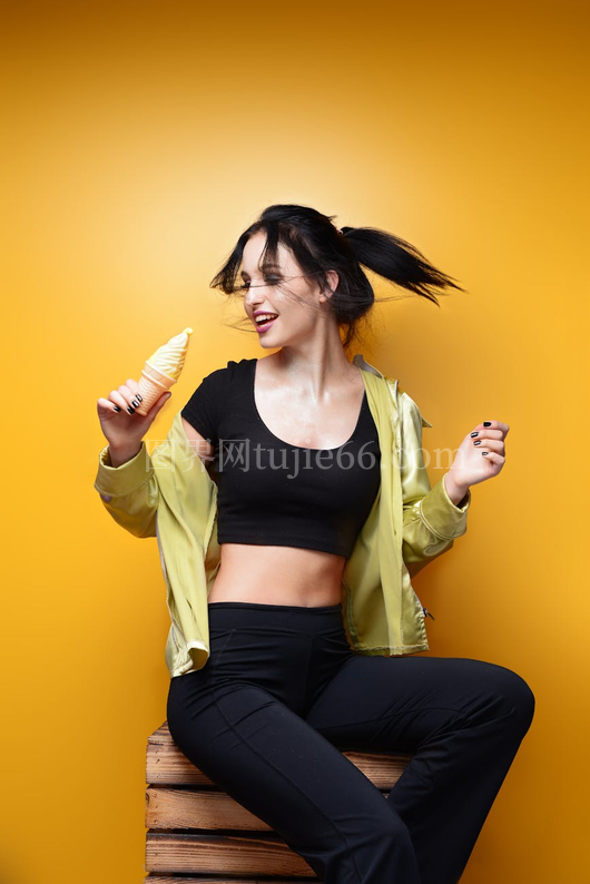 微笑运动装女性手握冰淇淋背景黄