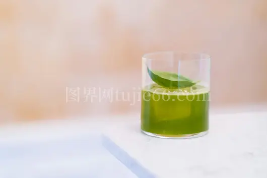 翠绿果汁配绿叶白桌优雅呈现