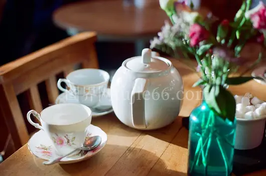 白色陶瓷茶壶近摄搭配粉红花束白瓷茶杯桌景