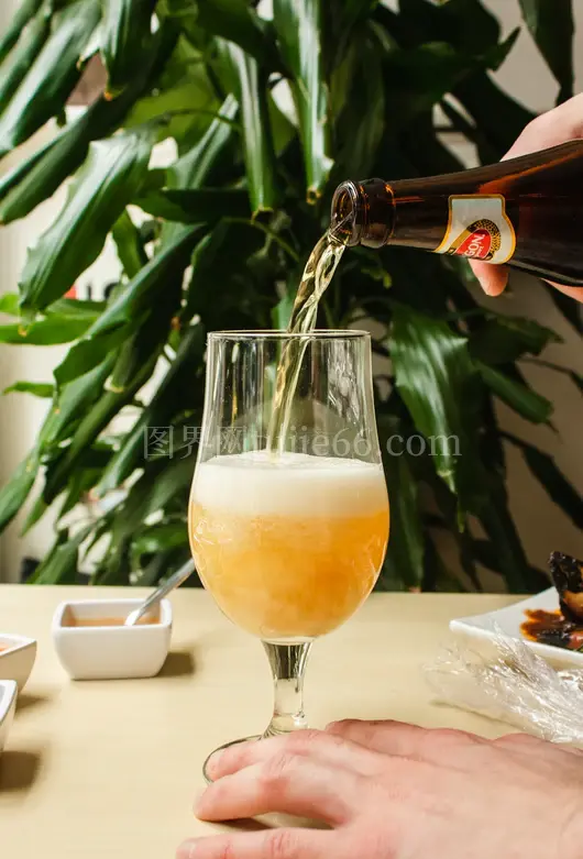 人物倒啤酒入透明酒杯