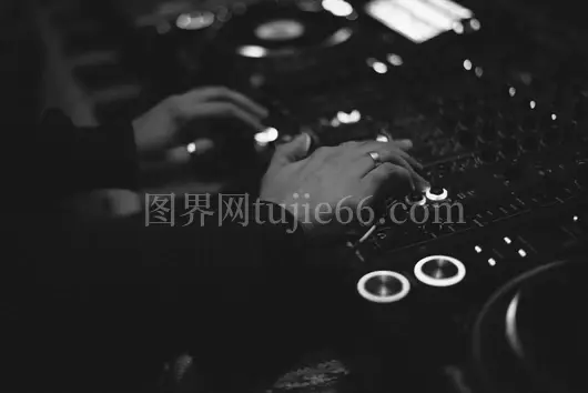 黑白背景中手调DJ混音器特写