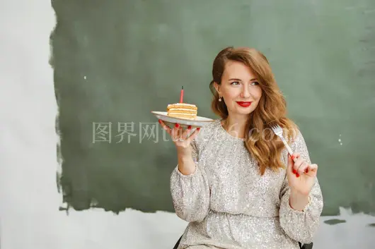 快乐女子手持蛋糕片烛光映照