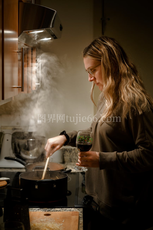 温馨厨房中手持酒杯烹饪的女性